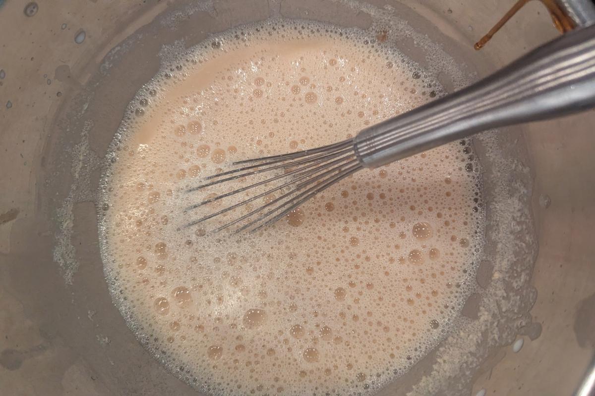 curdled milk and apple cider syrup in a bowl with a whisk.